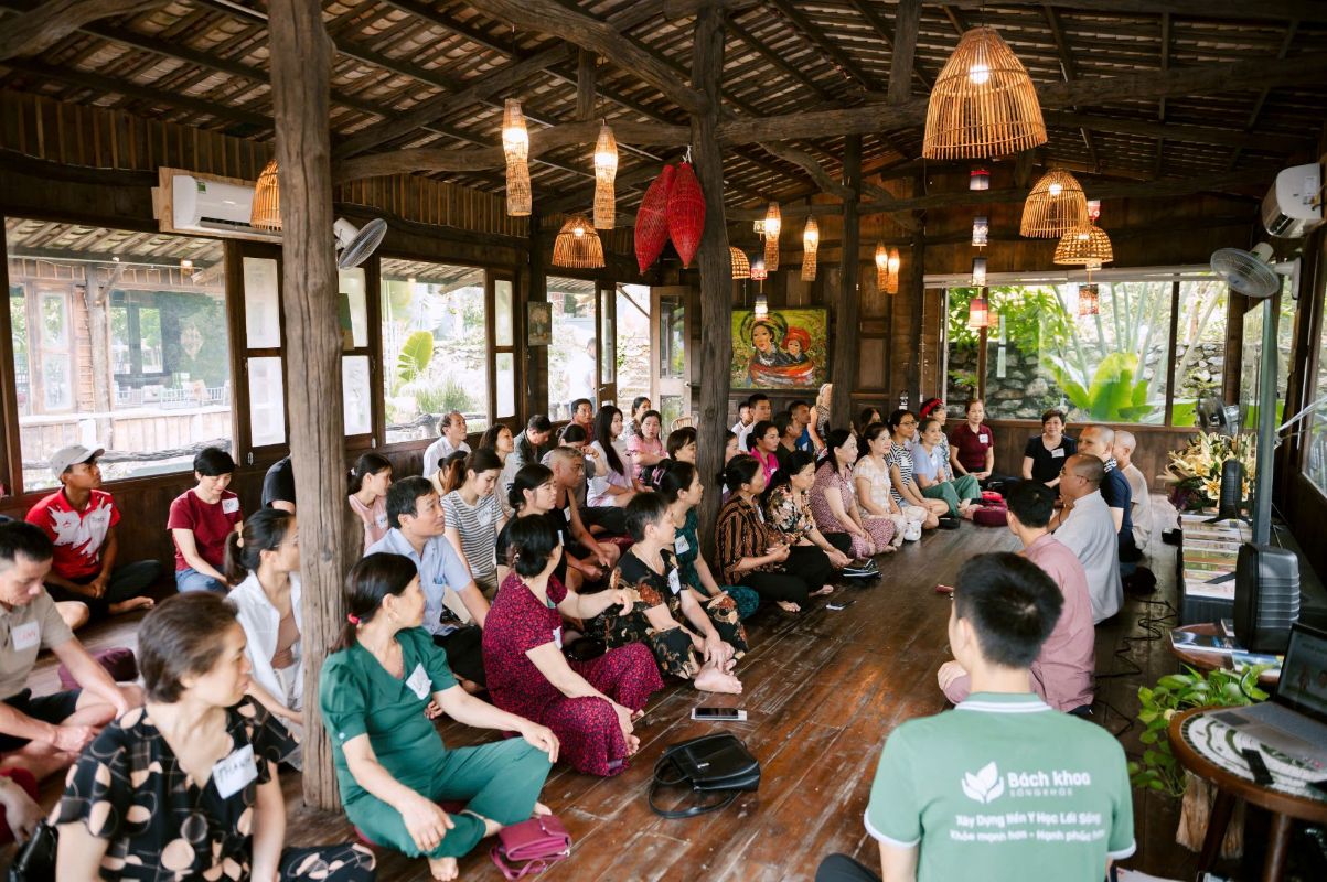 Học viên ngồi quanh nghe chia sẻ trong nhà gỗ